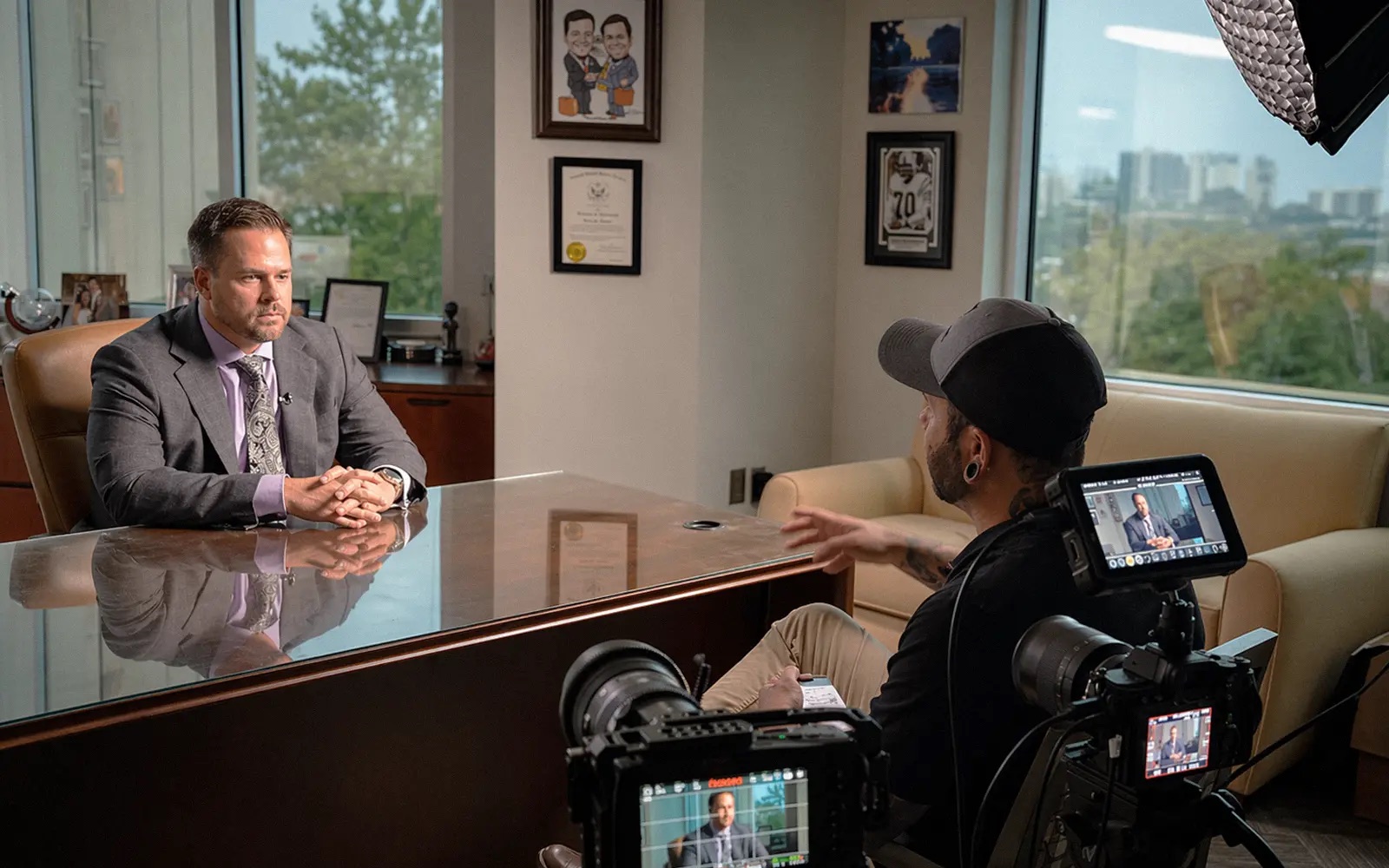 An attorney sitting at a desk being filmed by a camera operator