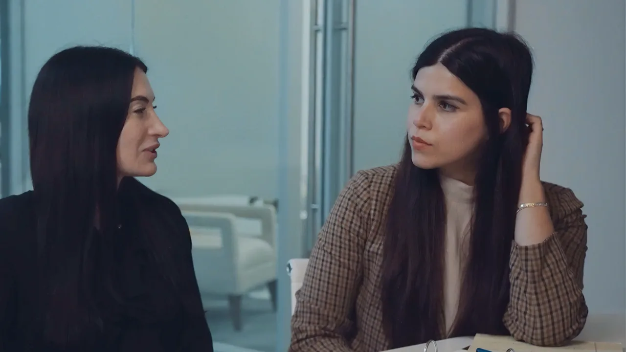 Two seated women talking across a long table in a law firm's office